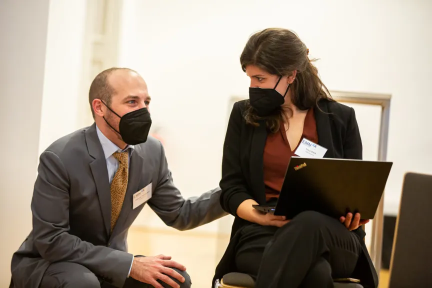Mann spricht mit einer Frau, die einen Laptop in der Hand hält