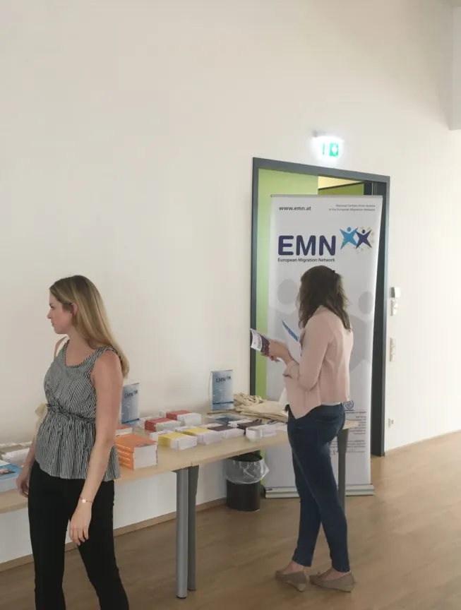 drei Frauen stehen bei einem Tisch mit Marketingunterlagen.