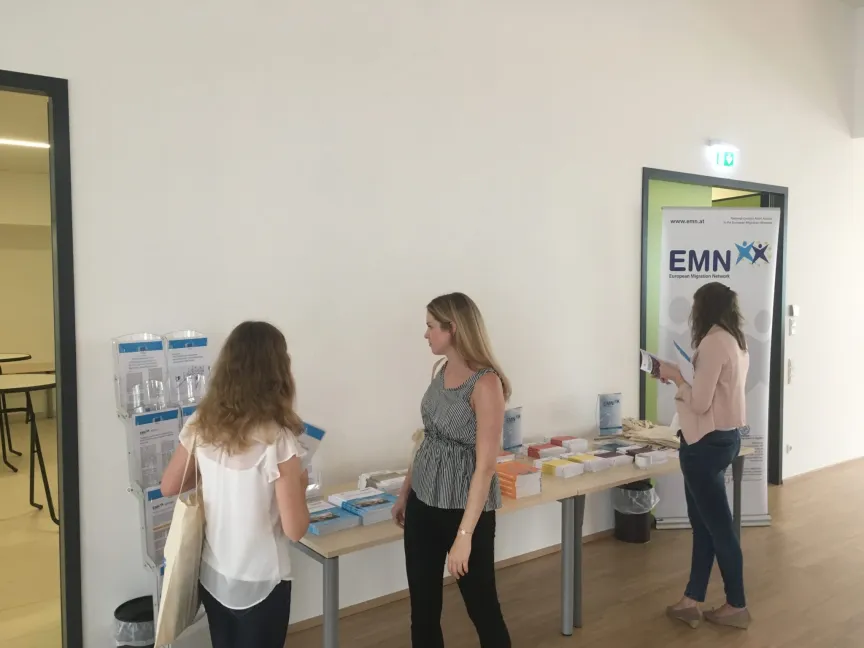 drei Frauen stehen bei einem Tisch mit Marketingunterlagen.