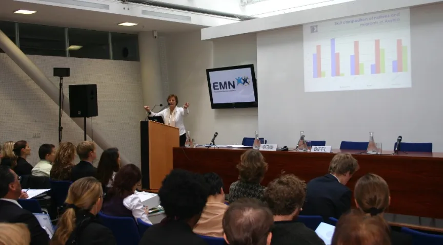 Vortrag mit Rednern und Rednerinnen sitzend an einem großem Tisch