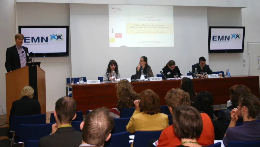 Vortrag mit Rednern und Rednerinnen sitzend an einem großem Tisch