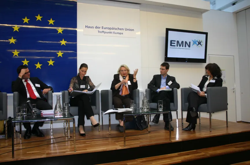 Vortrag mit Rednern und Rednerinnen sitzend an einem großem Tisch