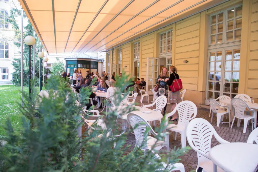 Garten und Terrasse. Gäste stehen zusammen und reden miteinander.