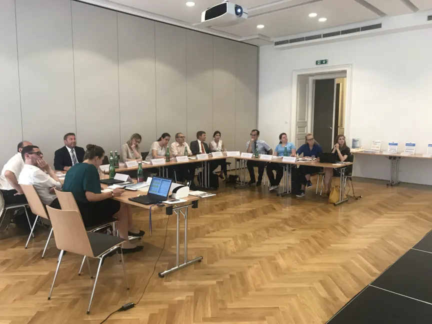 Besprechung mit mehreren Menschen in einem großen Raum mit Leinwand