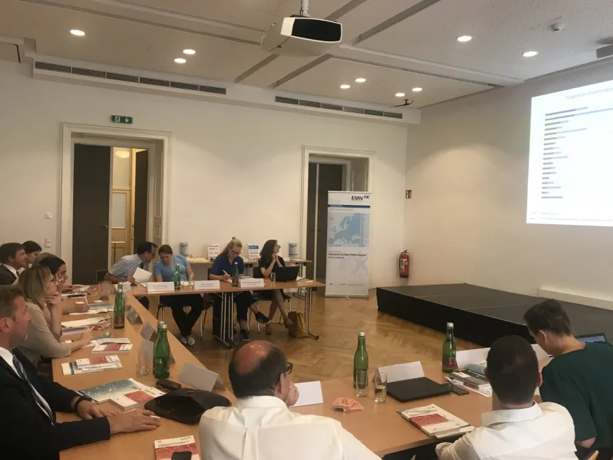 Besprechung mit mehreren Menschen in einem großen Raum mit Leinwand