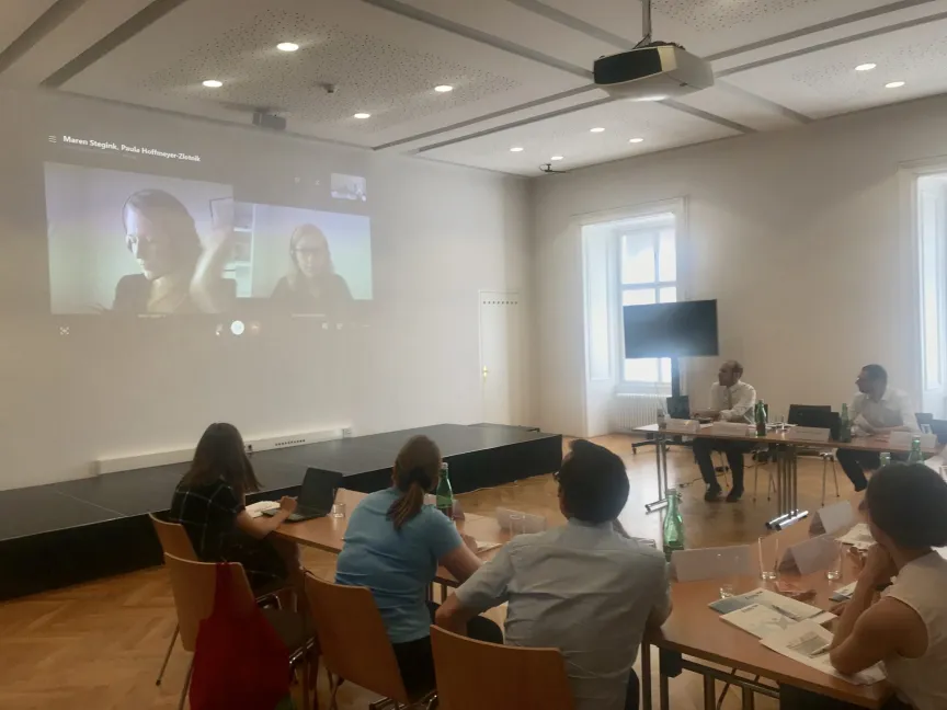 Besprechung mit mehreren Menschen in einem großen Raum mit Leinwand