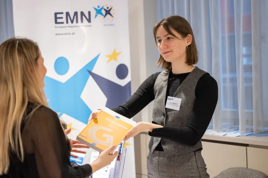 EMN-Conference- Picture of two women exchangign emn publications